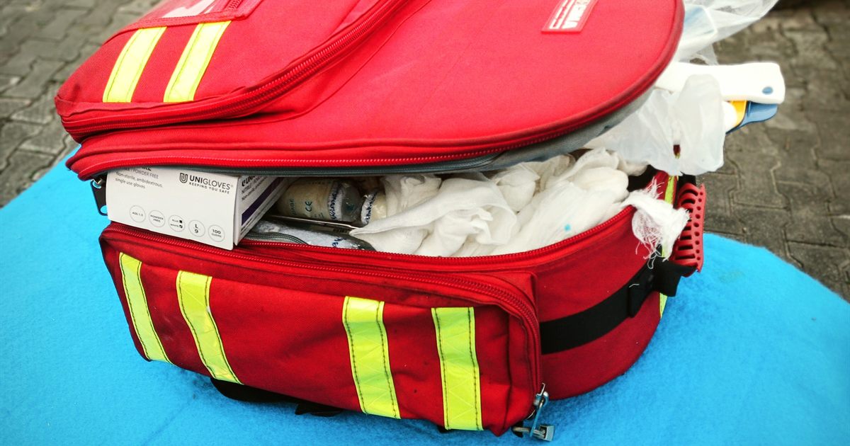 An open workplace first aid kit with dressings, plasters and gloves laid out to check expiry dates