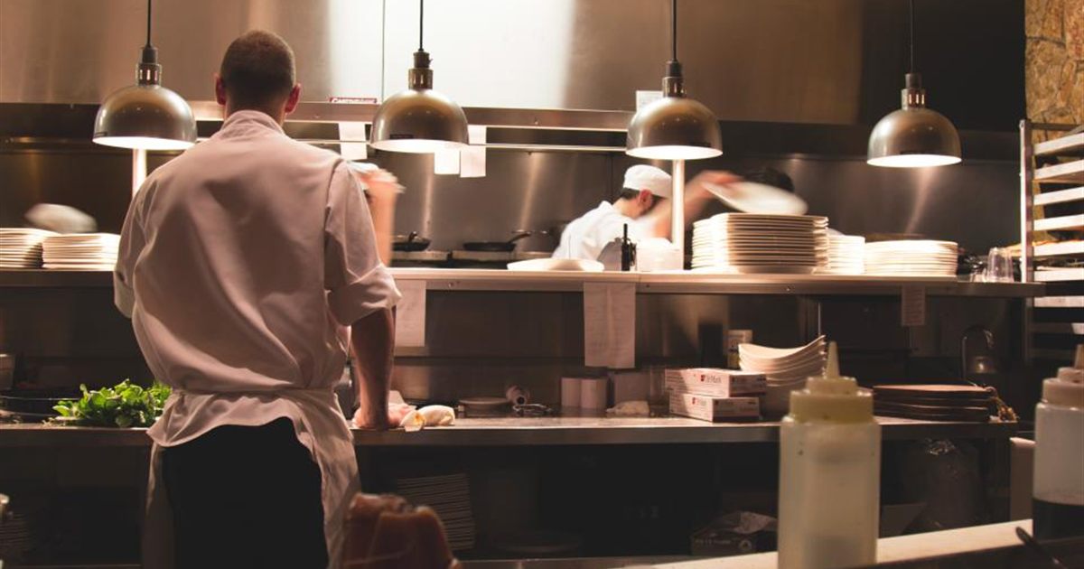 Chefs working on the line in a busy commercial restaurant kitchen — the environment a catering first aid kit is designed for